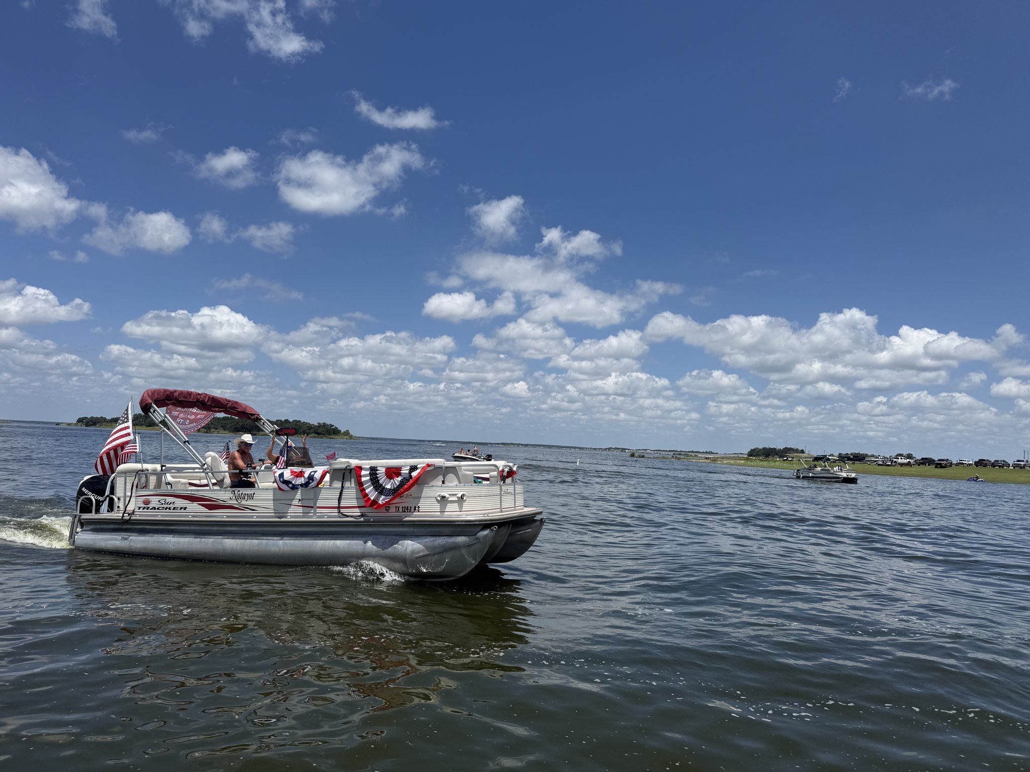 A pontoon boat trimmed with red, white and blue bunting in a holiday boat parade on Lake Somerville
