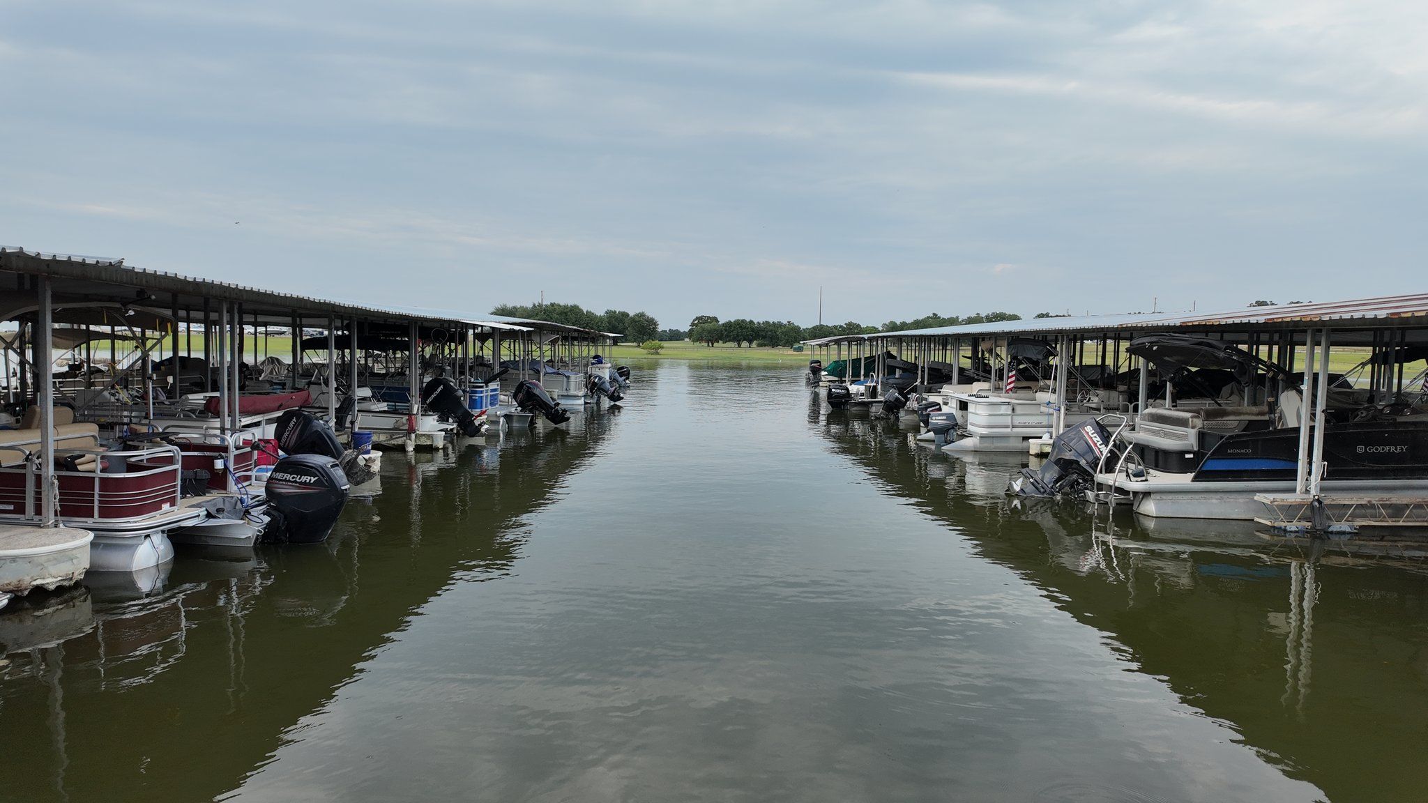 Covered boat slips at Overlook Park & Marina with pontoons and outboards moored on both sides of the fairway