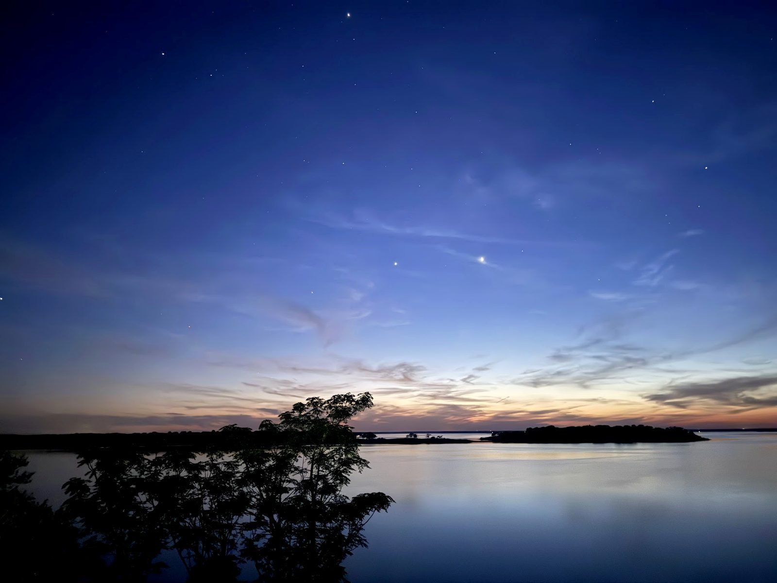 The last blue and gold light fading over a still Lake Somerville, with the first stars appearing above a dark treeline.