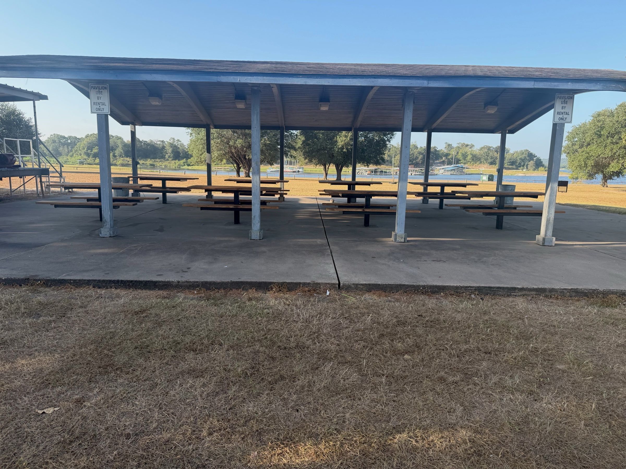 The covered pavilion with rows of picnic tables under a wide roof, with the lake and shoreline docks behind it.