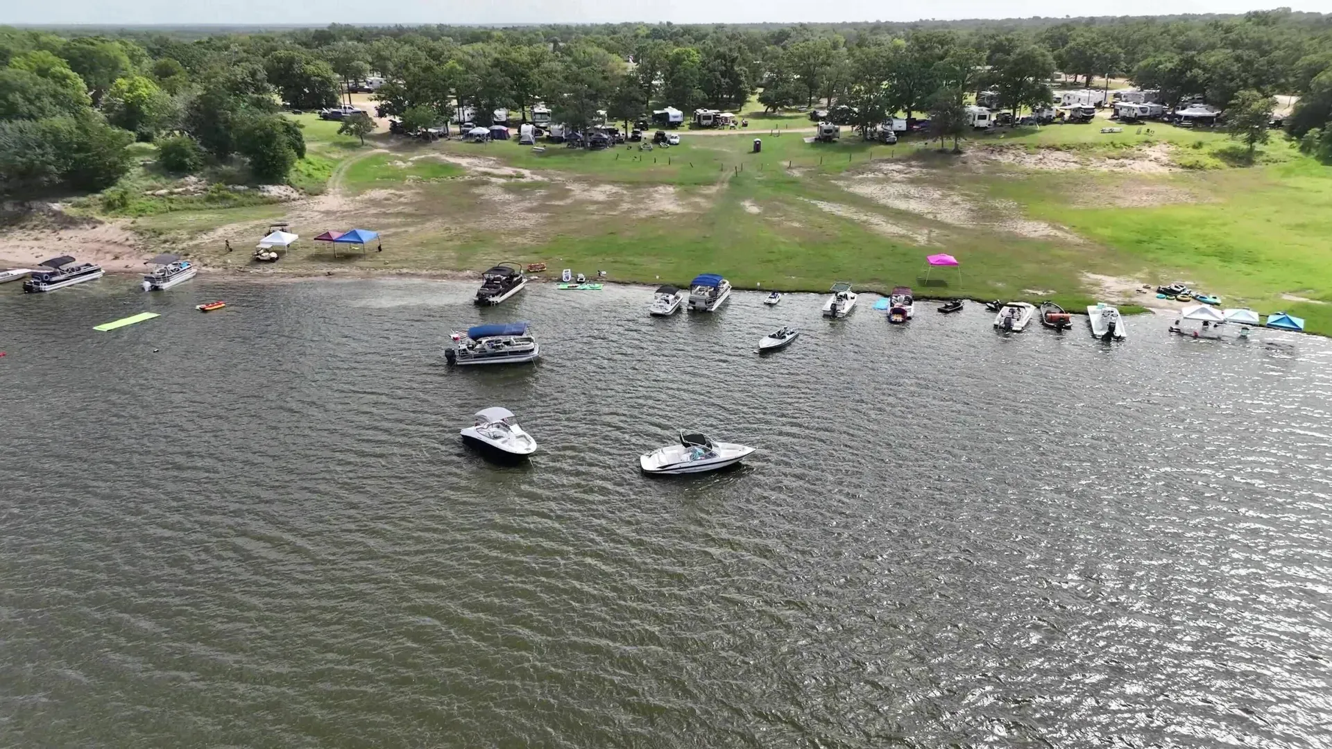 Rows of RVs and campers on the grass above the shoreline at Overlook Park & Marina, with boats pulled up along the water’s edge.
