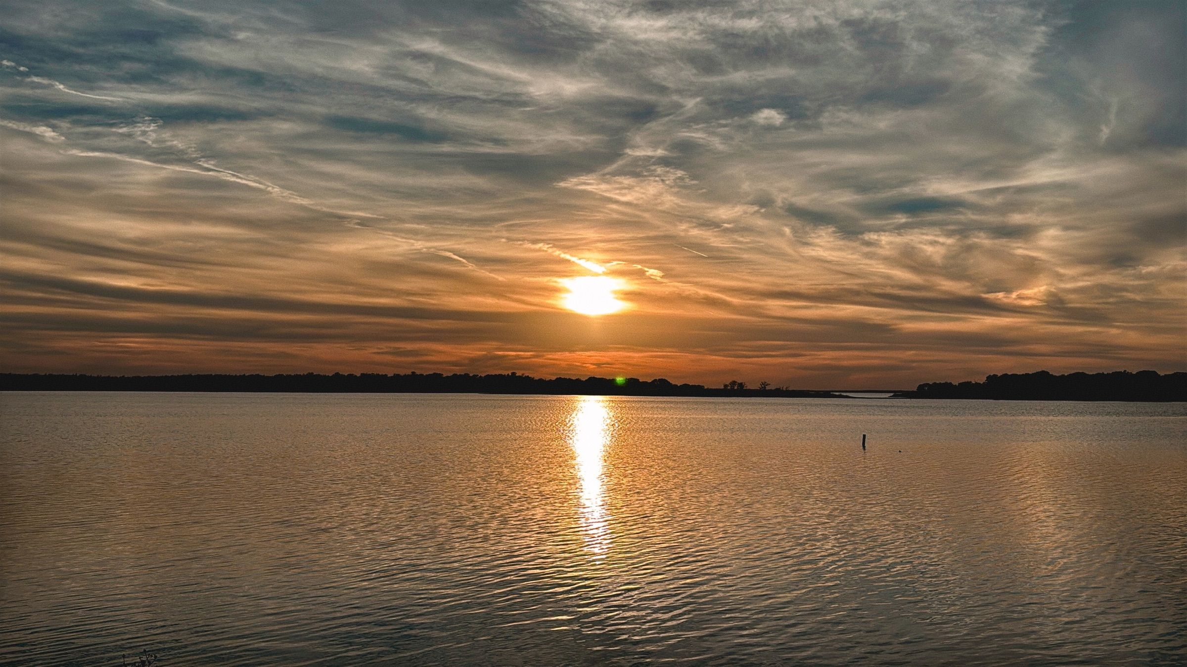 The sun setting low over rippled water on Lake Somerville